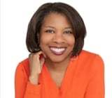 Professional headshot of a smiling woman with dark hair wearing an orange top